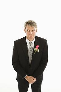 Groom with hands clasped in front of him