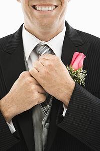 Close up of groom adjusting his tie