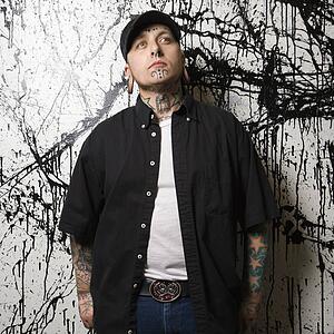 Tattooed and pierced man standing against paint splattered background
