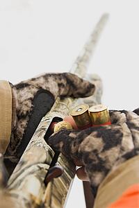 Gloved hands loading shell into shotgun.