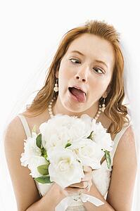 Portrait of Caucasian bride holding bouquet and making funny face.