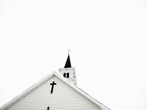 Top of white church with clear sky in background.