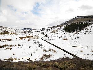 Railroad tracks in snow covered landscape leading towards small town