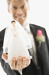 Groom holding out bride figurine in palm of his hand