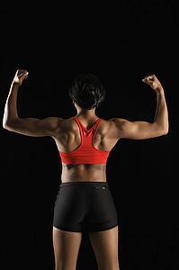 Back view of muscular African American woman with biceps flexed.