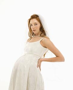 Pregnant Caucasian bride with hands on her back.