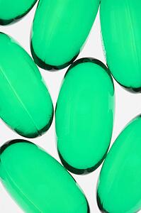 Close up of green capsule pills against white background.
