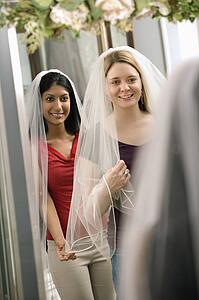 Women trying on veils and looking in mirror