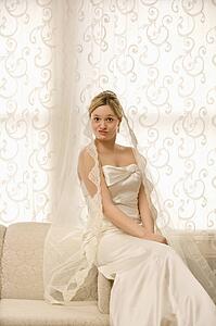 Portrait of Caucasian bride sitting on love seat making a funny expression.