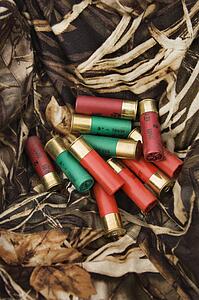 Still life shot of shotgun shells against camouflage clothing.