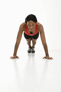 African American young adult woman doing push up and looking at viewer.