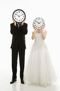 Groom and bride with clocks covering their faces