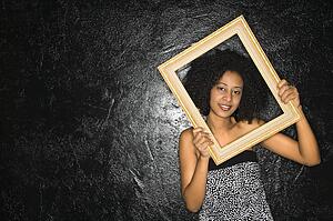 African-American woman holding frame over her face.