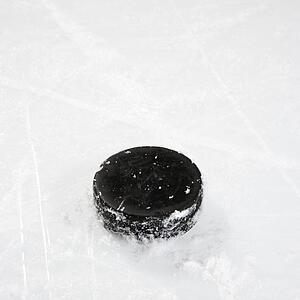 Black hockey puck on ice rink.