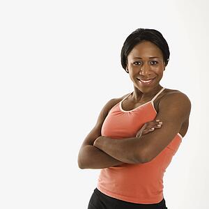 African American young adult woman in athletic wear smiling at viewer with arms crossed.