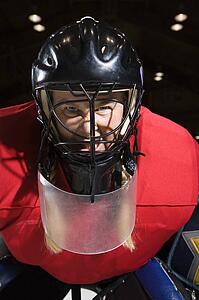 Woman hockey goalie wearing helmet sneering looking intimidating.