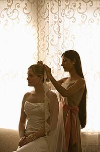 Bridesmaid placing veil on a bride