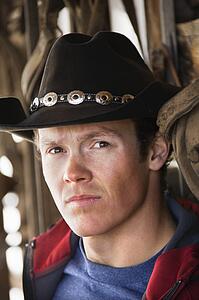 Young adult male wearing cowboy hat looking at viewer