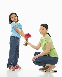 Girl giving her mother a bouquet of flowers.