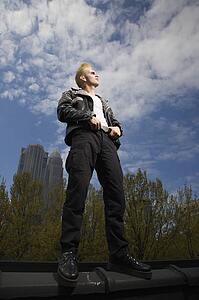 Portrait of male punk standing on ledge with skyline in background