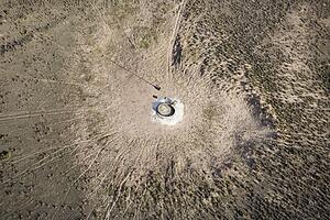 Aerial view of livestock watering pump in the middle of empty field.