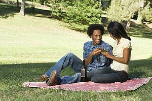 Couple having romantic picnic in park toasting wine