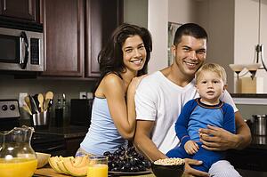 Family with toddler son in kitchen at breakfast smiling at viewer
