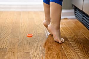 Feet of toddler boy with magnets in front of refrigerator.