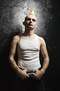 Portrait of young male punk holding belt buckle.
