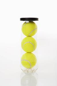 New tennis balls stacked in plastic container