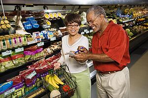 Man and woman in grocery store smiling and pointing at shopping list