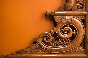 Ornate wooden furniture carving against orange wall