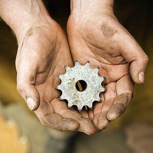 Dirty metal-smith's hands holding metal leaf