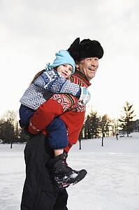 Man holding little girl piggyback style smiling and looking at viewer