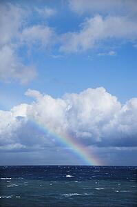 Seascape of the Pacific Ocean near Maui, Hawaii with rainbow and clouds.