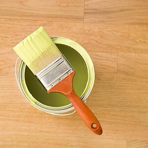 High angle view of paintbrush resting on paint can on wood floor