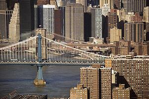 Aerial view of New York City's Manhattan Bridge with Brooklyn Bridge and Manhattan buildings in background.