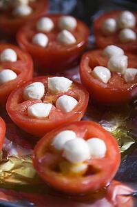 Group of tomatoes and mozzarella cheese on aluminum foil.