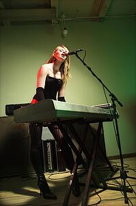 Woman singing into microphone and playing the keyboard