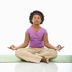 Girl sitting on floor in yoga lotus posture with eyes closed