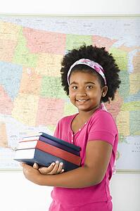 Girl standing in front of map holding stack of books