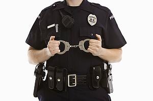 Close up of mid adult Caucasian policewoman holding locked handcuffs.