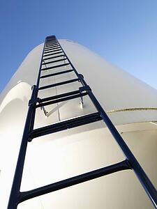 Low angle view of metal grain storage silo with ladder assending to top.