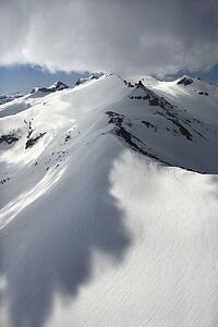Aerial of snow covered mountain with clouds