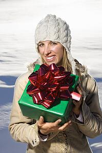 Woman outdoors in winter attire holding present