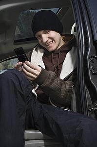 Caucasian male teenager text messaging with cellphone.