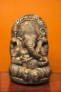 Statue of Hindu elephant Ganesha against orange wall