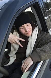 Male teenager making hand gesture while sitting in car