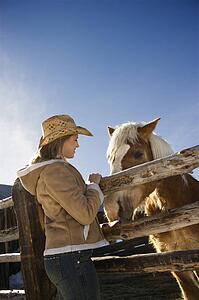 Woman standing at fence with horse