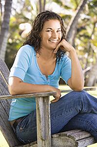 Female sitting in chair with hand on chin smiling